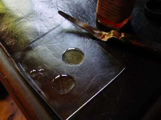 Festészeti médium cseppjei üveglapon, mellette festőkés