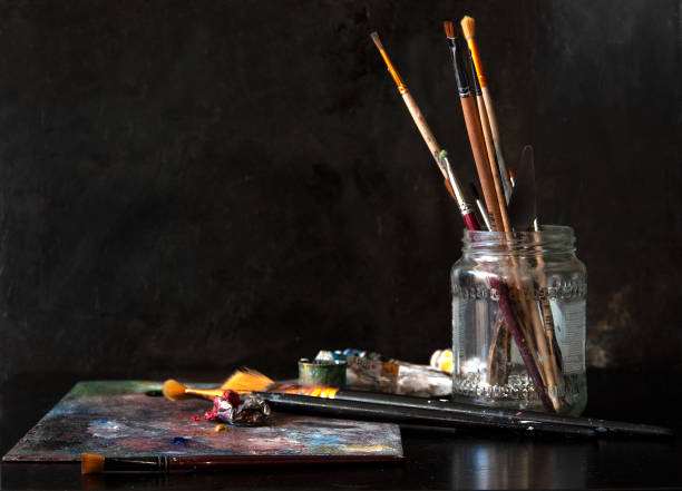 Festőműhely ecsetekkel, palettával és festékekkel egy asztalon